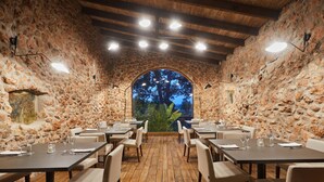 Un restaurante con paredes de piedra, piso de madera y mesas dispuestas para comer.