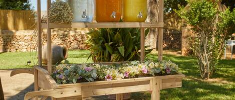 A wooden outdoor cart with jars and a flower arrangement.
