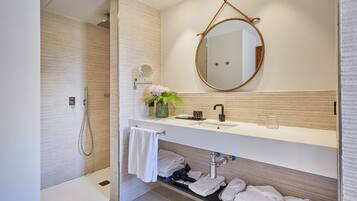 A modern bathroom with a shower, a sink with a mirror, and a towel rack.