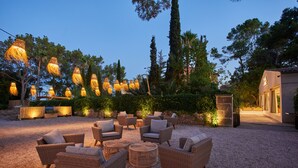 Un espacio al aire libre con mobiliario de mimbre e iluminación decorativa colgante.