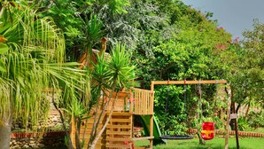 A wooden play structure with a slide and a swing set in a lush garden. - Scilla e Cariddi Bed&Breakfast (Messina)