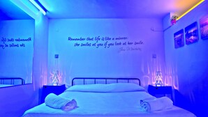 A bedroom with a bed, two bedside tables, a wall with a quote, and a wall-mounted shelf with a plant. - Scilla e Cariddi Bed&Breakfast (Messina)