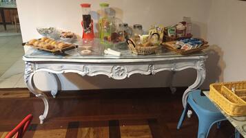 Une table à manger avec divers aliments et récipients, une chaise bleue et un panier en osier.