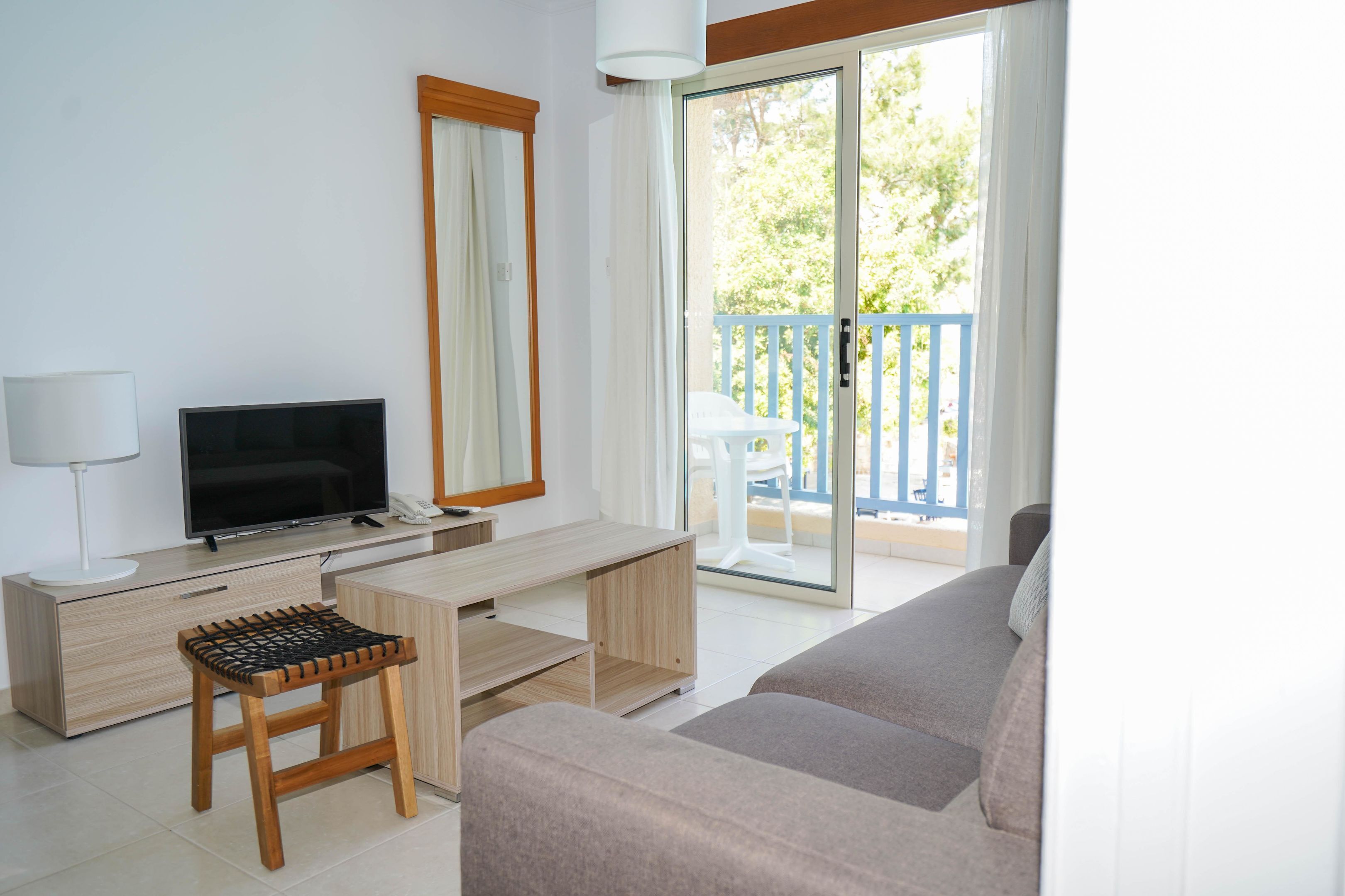 Ein modernes Wohnzimmer mit Flachbildfernseher, Schreibtisch, Sessel und Sofa.