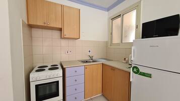 A compact kitchen with a stove, oven, sink, and a refrigerator.