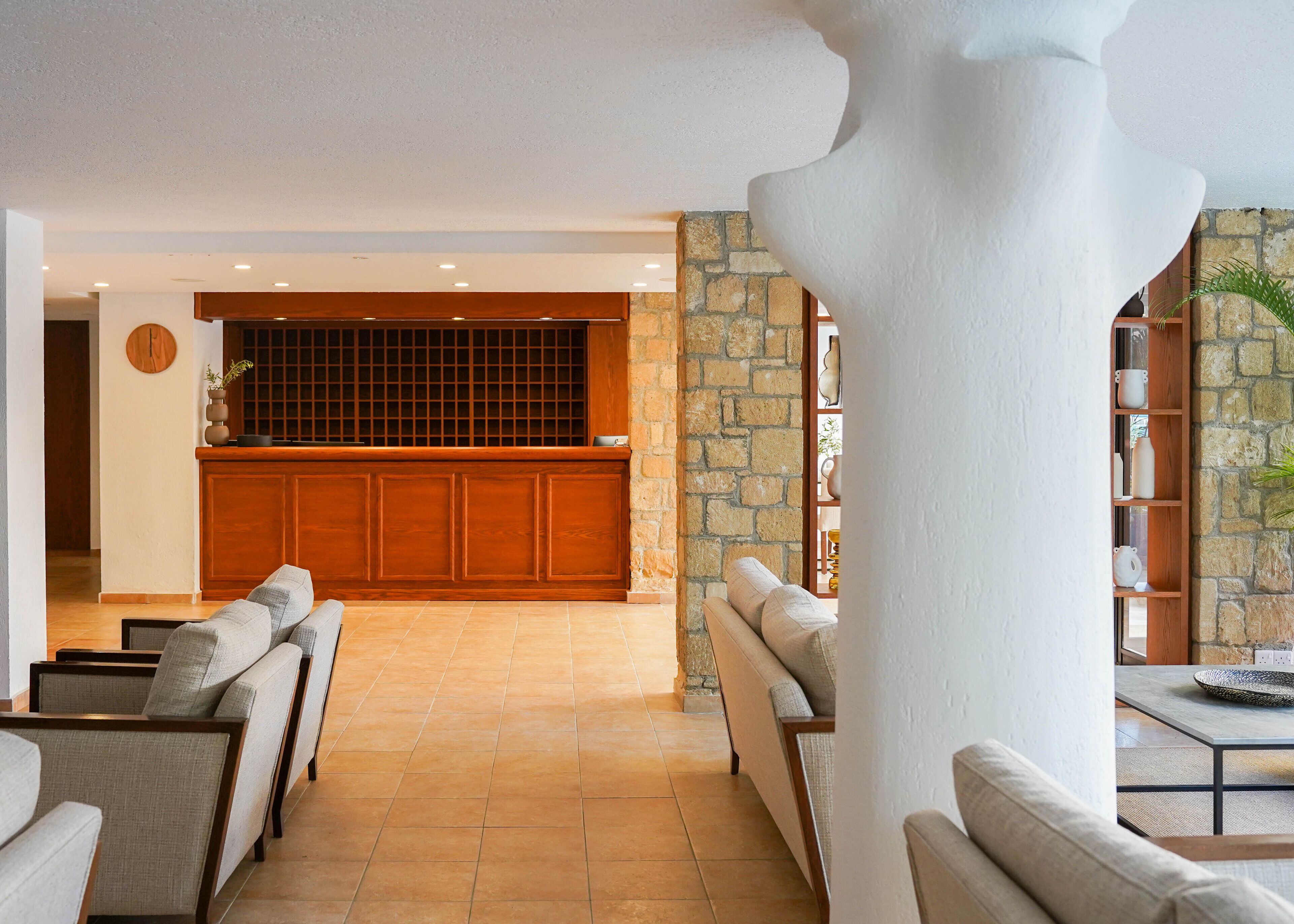 A spacious lobby with a stone wall, a wooden reception desk, and seating areas.