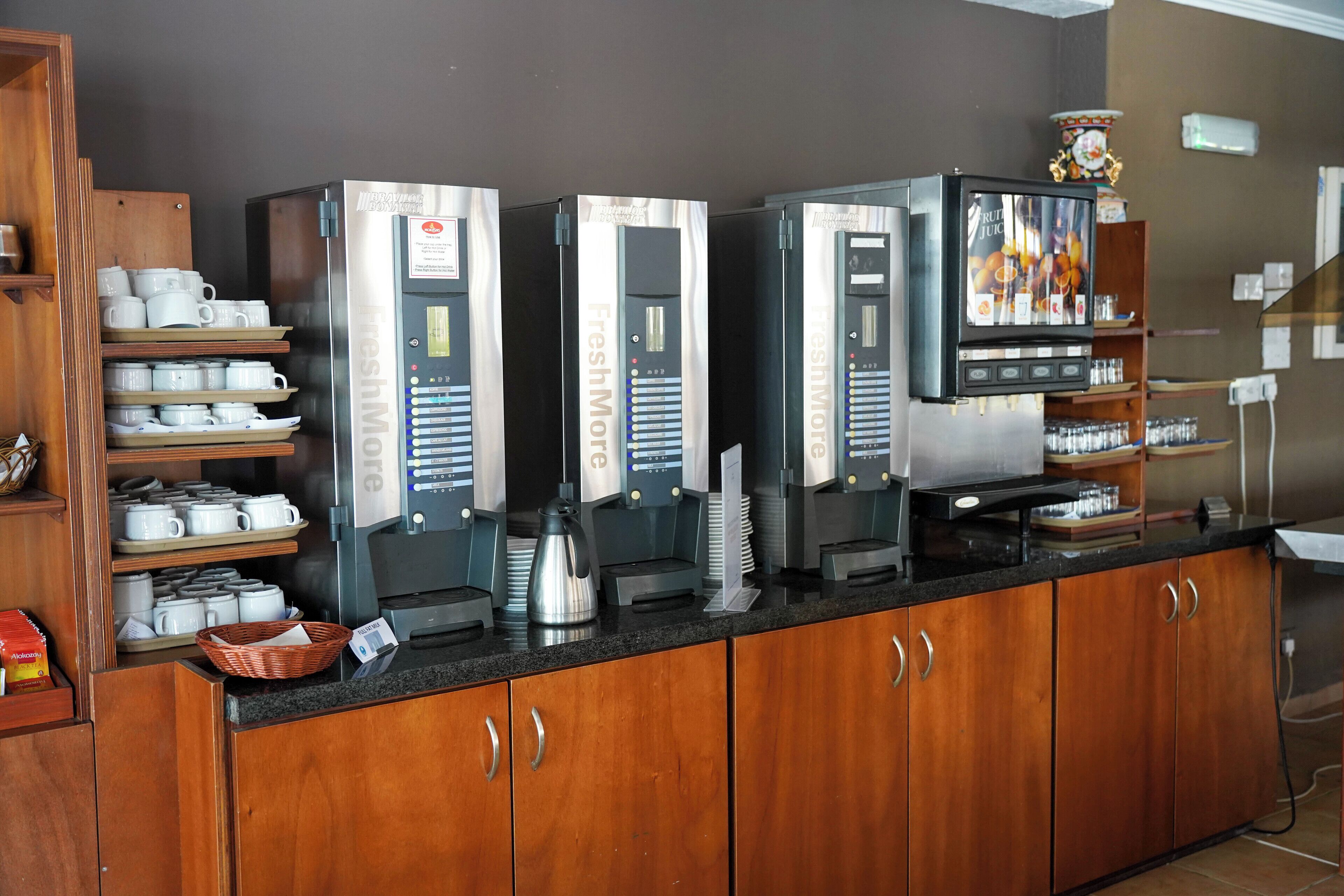 A coffee station with multiple coffee machines and a variety of coffee cups and mugs.