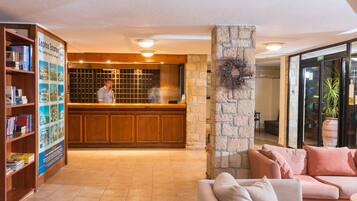 A reception area with a wooden counter, a stone pillar, a couch, and a bookshelf with brochures.