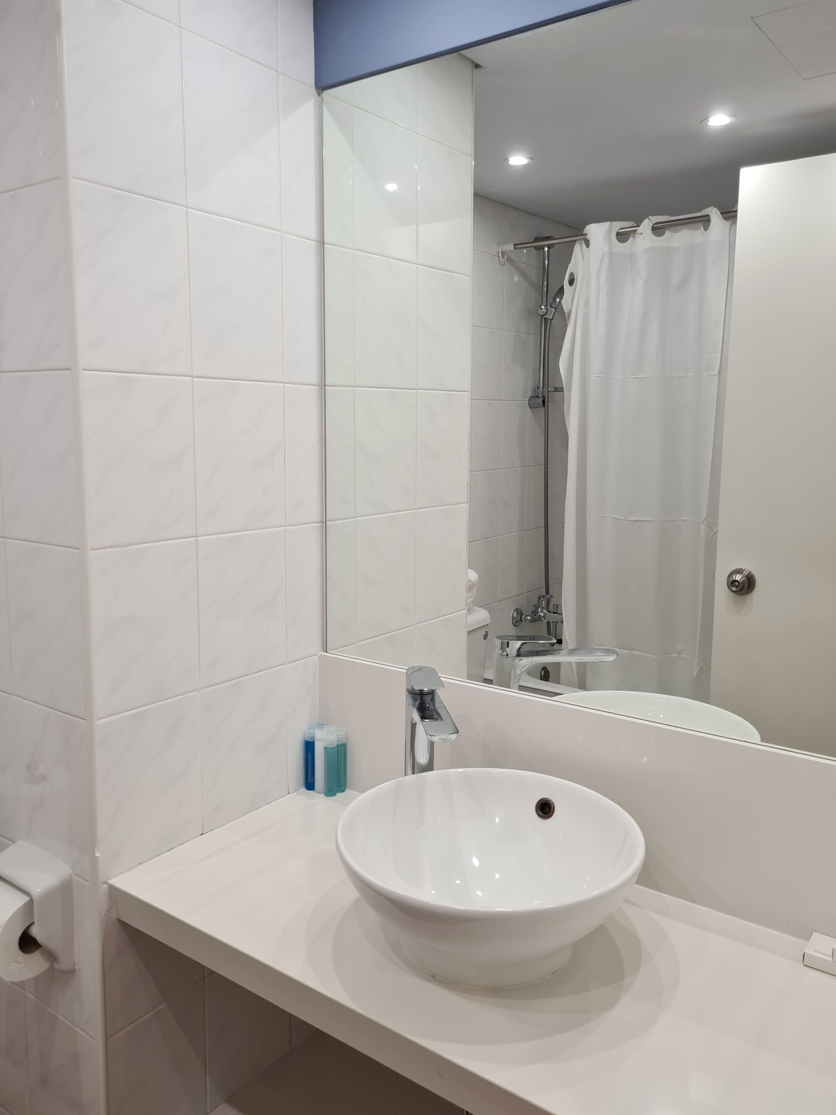 A modern bathroom with a white sink, mirror, and shower.