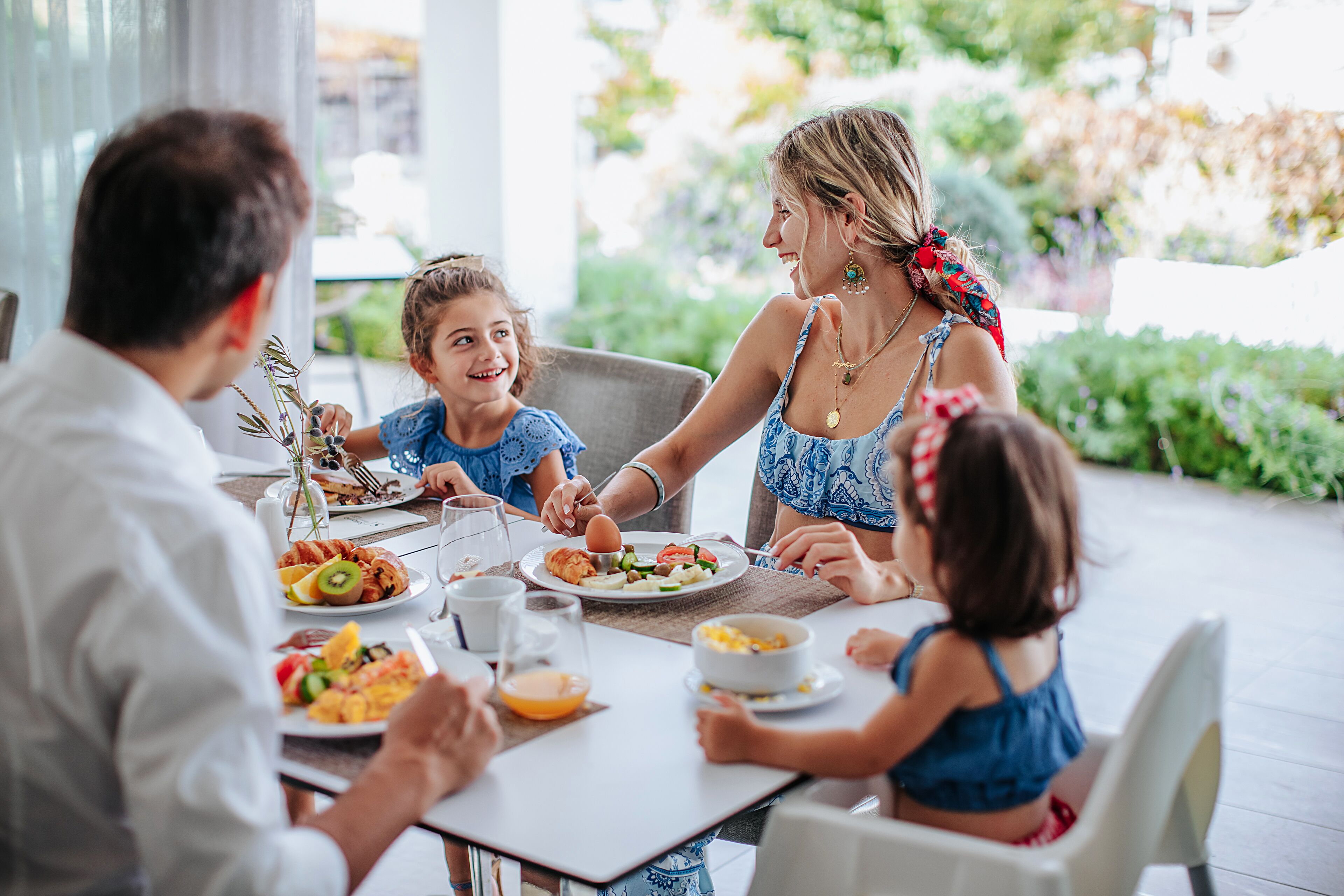 Une famille est assise à une table en plein air et déguste différents plats, notamment des fruits et des légumes.