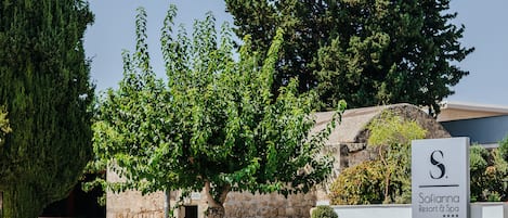Une enseigne indiquant l’emplacement du Sofia Inn Resort & Spa, entourée de verdure et d’éléments d’architecture en pierre.
