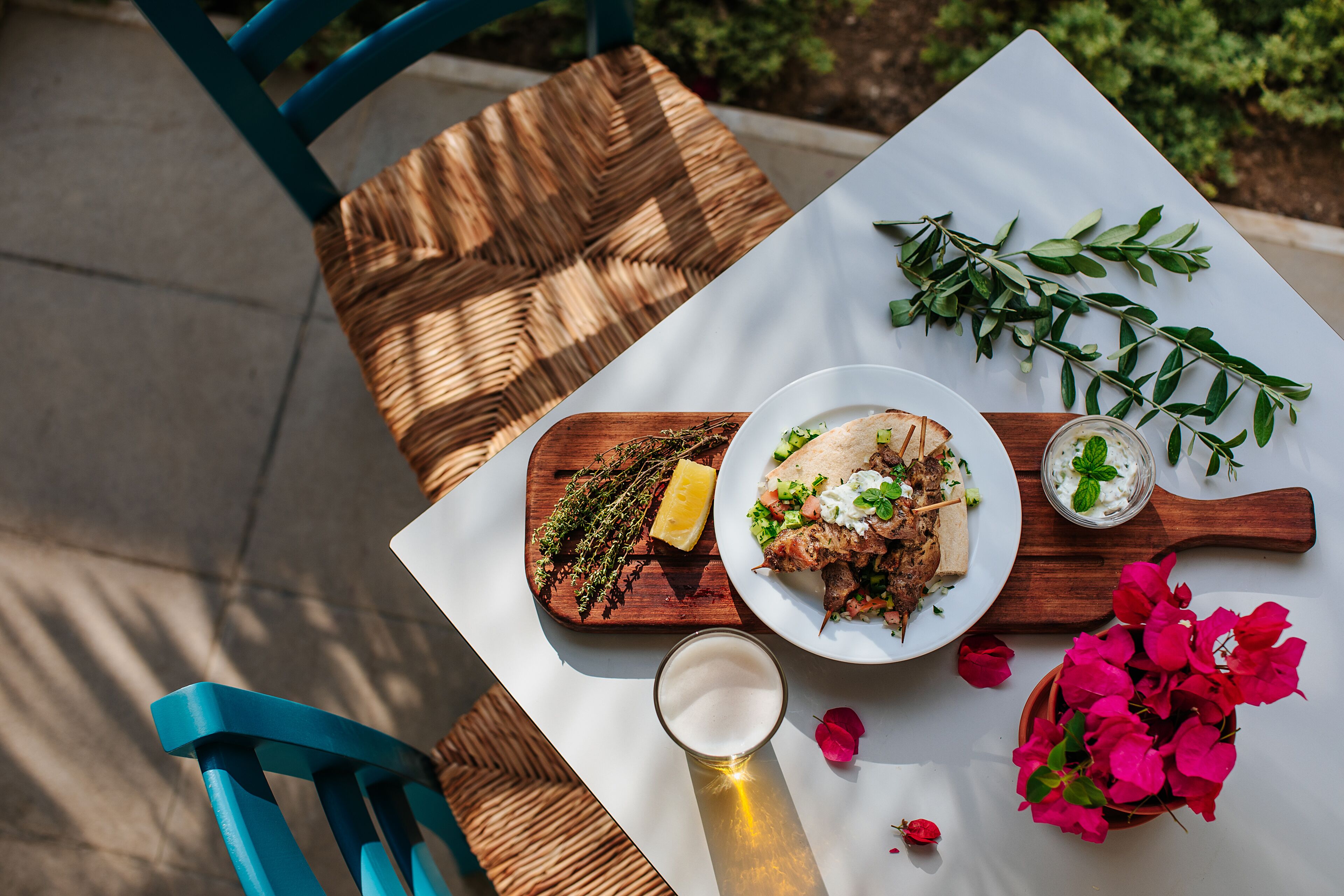 A table with a meal, a glass of beer, and decorative flowers.
