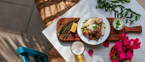 A table with a meal, a glass of beer, and decorative flowers.