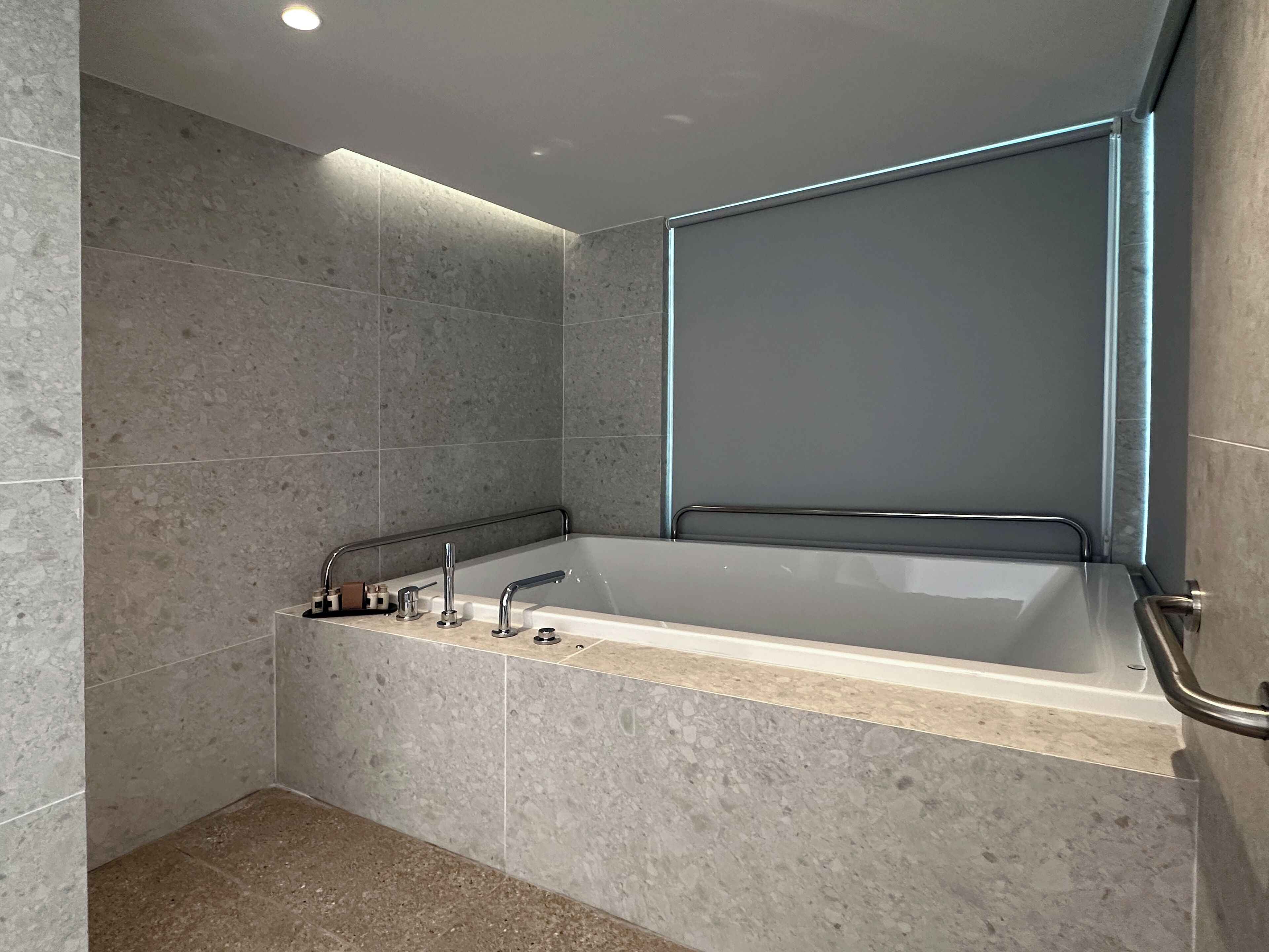 A modern bathroom with a freestanding bathtub, a handheld showerhead, and a glass shower enclosure.