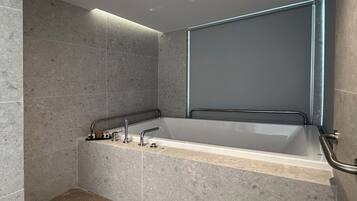 A modern bathroom with a freestanding bathtub, a handheld showerhead, and a glass shower enclosure.