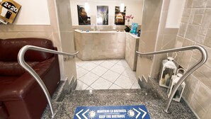 A hotel lobby with a reception desk, a red leather couch, and a sign instructing to keep distance. - Hotel Colombo (Naples)