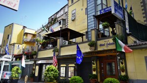 A hotel with balconies, multiple flags, and a sign indicating it is a hotel. - Hotel Colombo (Naples)