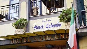 Hotel Colombo with a signboard, a balcony with plants, and a flag. - Hotel Colombo (Naples)