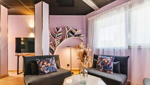 A modern living room with two dark sofas, a glass coffee table, and a unique bookshelf. - The Originals City, Hôtel Éclipse (Decines-Charpieu)