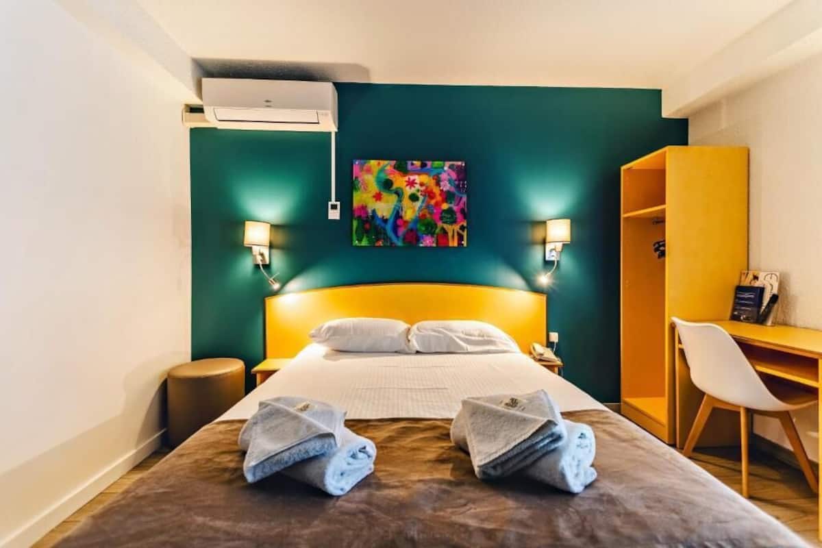 A hotel room with a bed, a desk, and a chair.