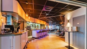 A modern bar area with a wooden floor, bar stools, and a counter with a menu. - The Originals City, Hôtel Éclipse (Decines-Charpieu)