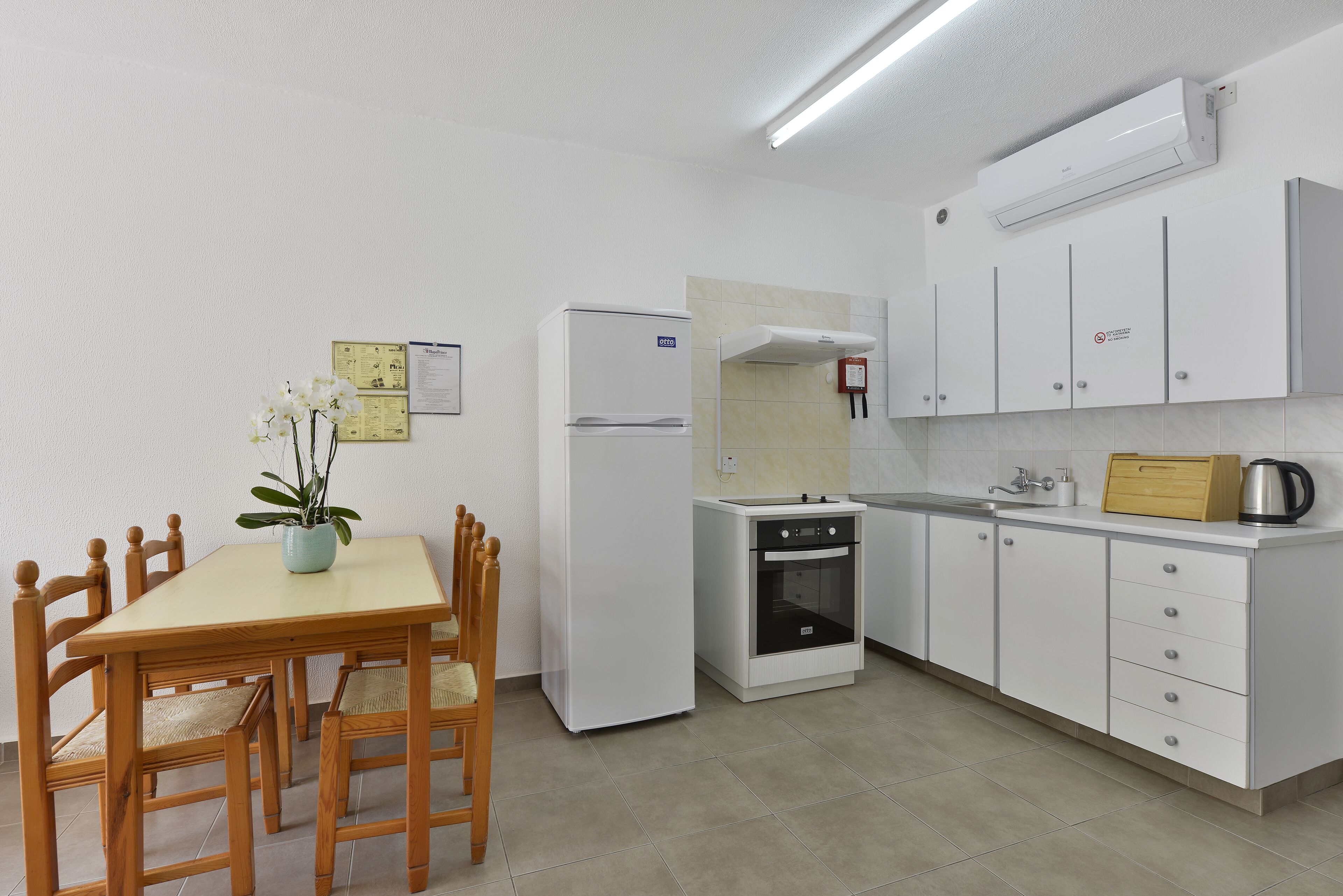 A compact kitchen with white cabinets, a built-in oven, and a small dining table with chairs.
