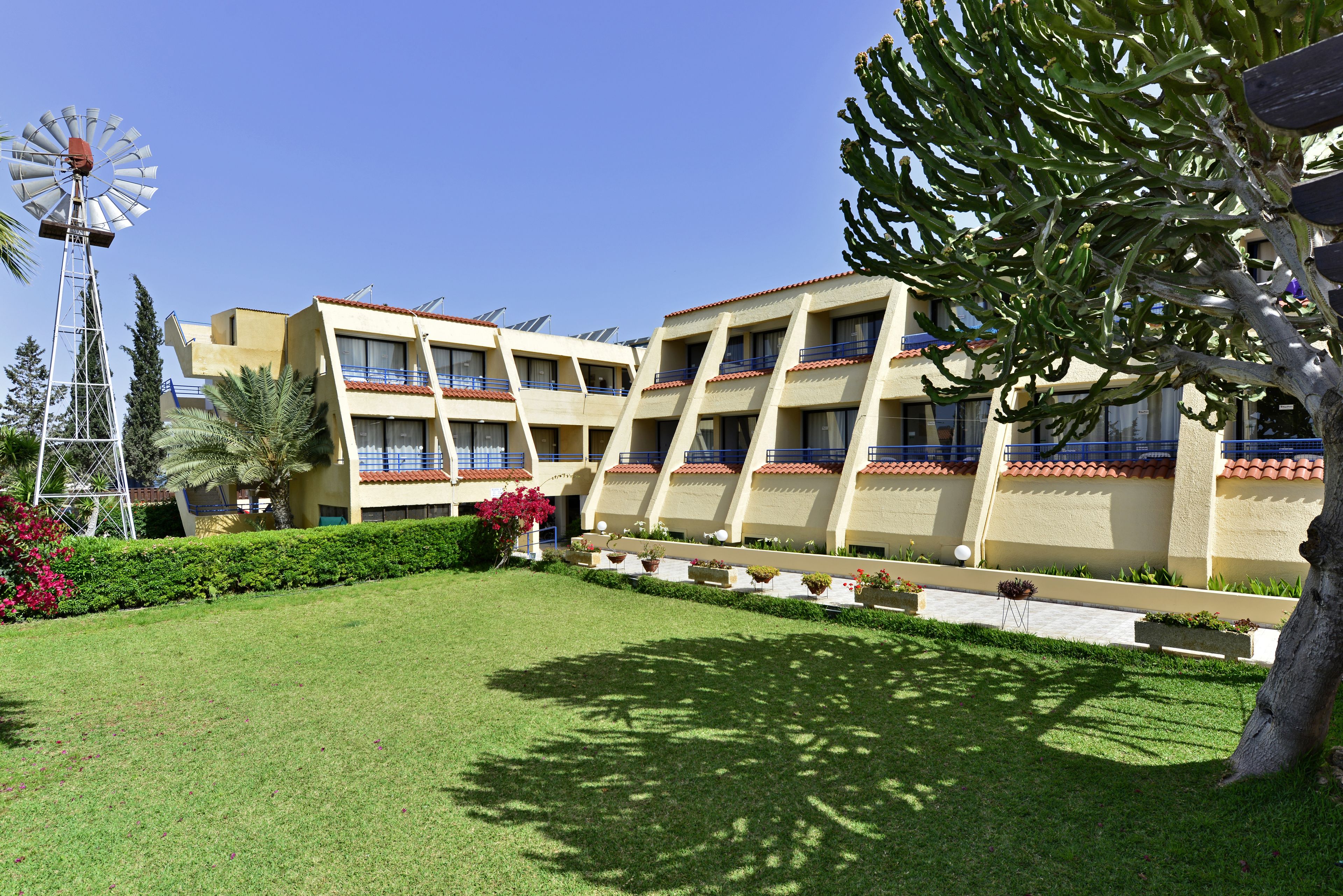 A hotel with multiple floors, a windmill, and a well-maintained garden.
