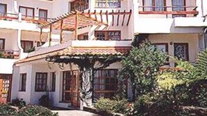 A multi-story building with balconies, a tiled roof, and a garden area. - Vila Ventura Apartment Hotel (Santa Cruz)