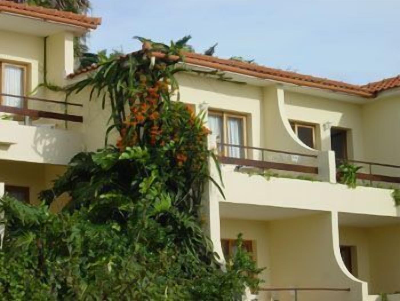 Un immeuble à plusieurs étages doté de balcons, entouré d’une végétation luxuriante et de plantes.