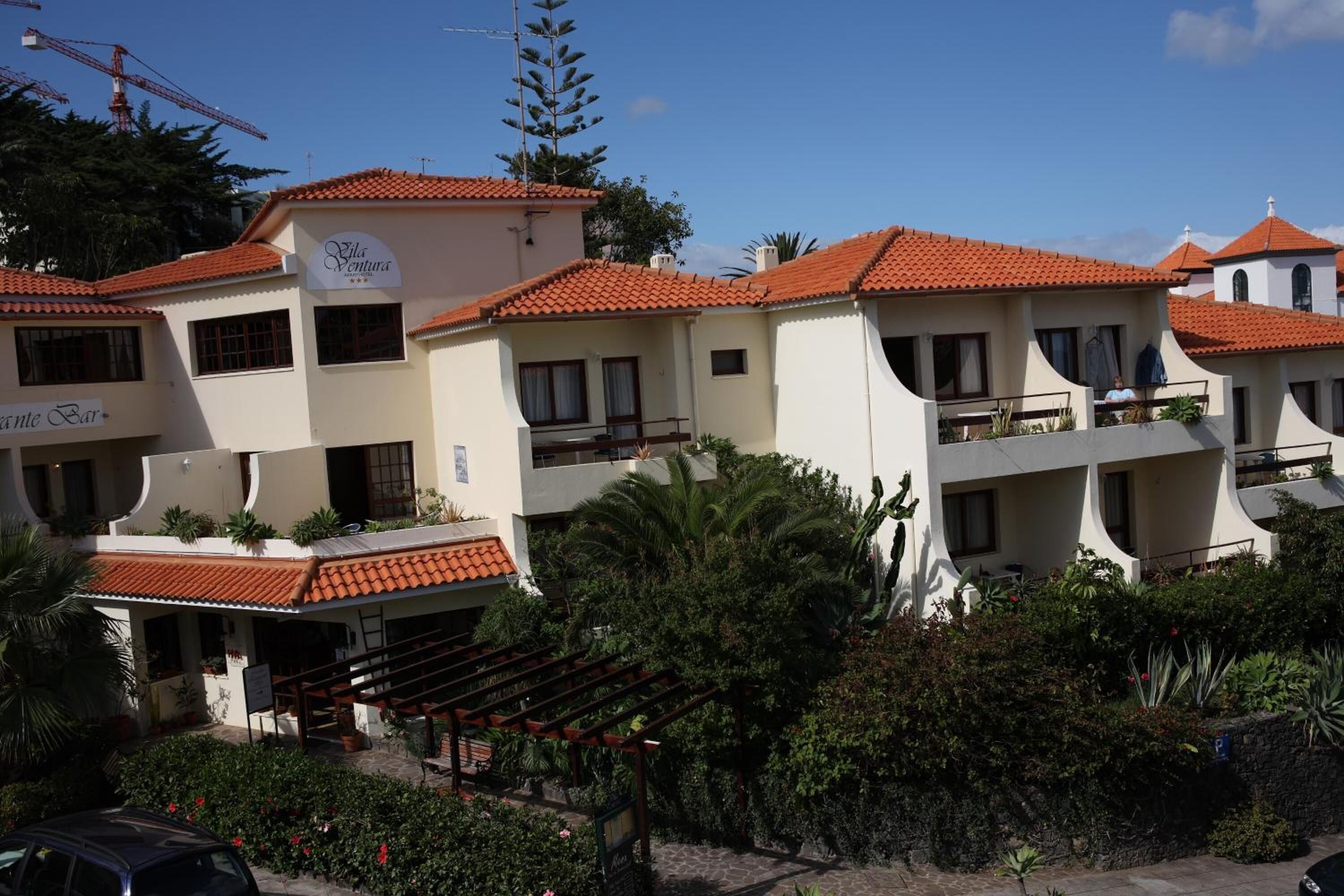 Un immeuble à plusieurs étages, doté d’un toit recouvert de tuiles rouges, de balcons et d’une enseigne indiquant « Villa Ventura ».
