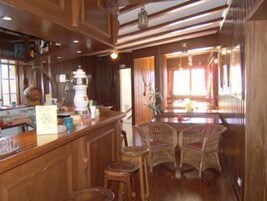 Un intérieur en bois avec un espace bar, des chaises en osier et un comptoir où sont exposés divers articles.
