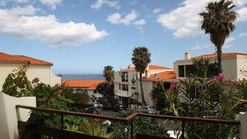 A coastal residential area with buildings, palm trees, and a view of the sea.
