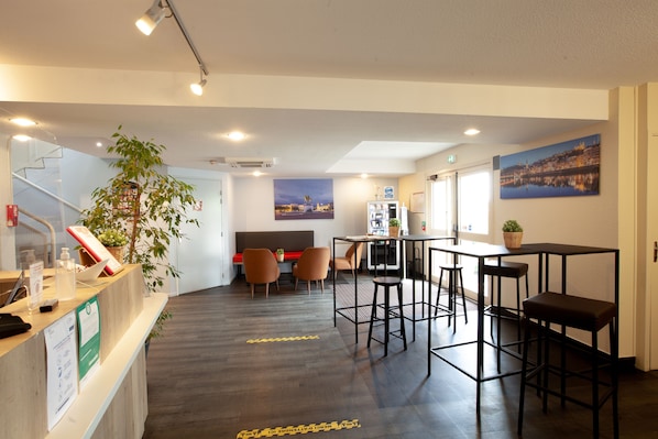 Vestíbulo de hotel con mostrador de recepción, zona de estar y bar.
