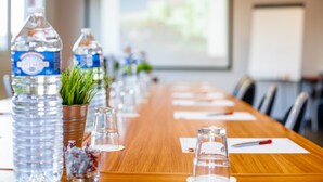 A conference table with water bottles, a potted plant, and glassware. - Best Hotel Lyon St Priest (Saint-Priest)