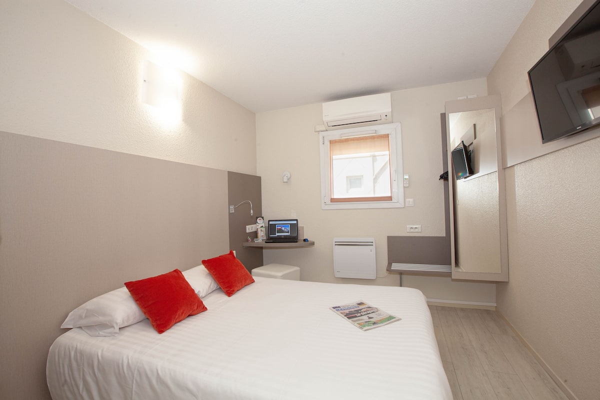Une chambre d’hôtel équipée d’un lit, d’un bureau, d’un miroir et d’un appareil de climatisation.