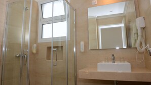 A bathroom with a glass-enclosed shower, a sink with a mirror, and a towel rack.