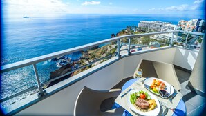 A balcony with a table set for two, overlooking a coastal view with buildings and a ship in the distance. - Hotel Duas Torres (Funchal)