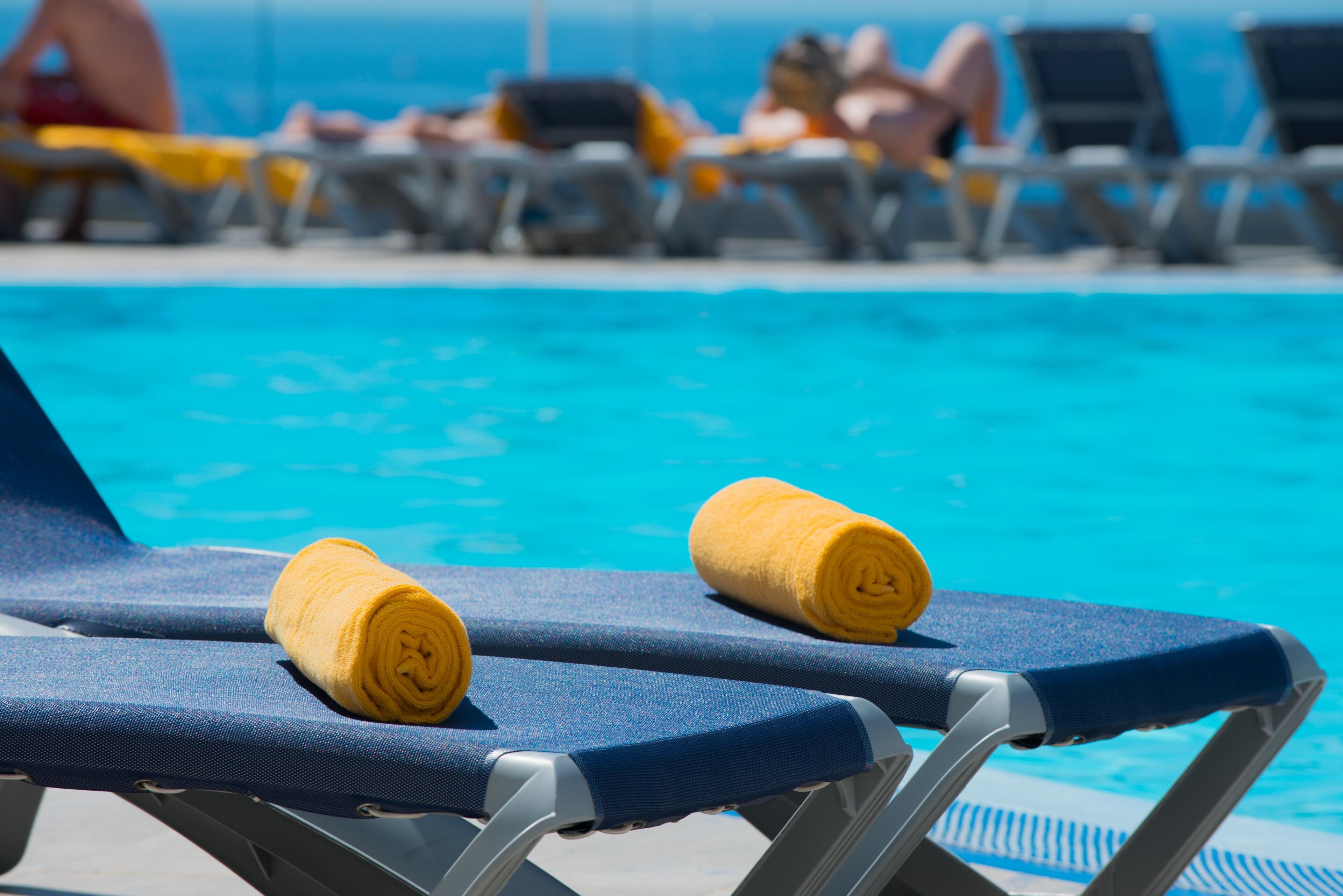 Ein Poolbereich mit blauen Liegestühlen und gelben Handtüchern.
