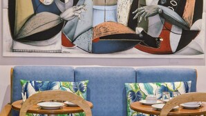 A room with a blue sofa, wooden chairs, and a table with plates and cups. - ASPA Studios - Urban Conscious Living (Funchal)