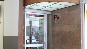 A building entrance with a glass door, a parking sign, and a tiled floor.