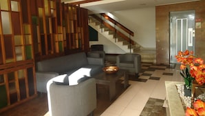 A modern lobby with a grey sofa, armchairs, a coffee table, and a staircase.