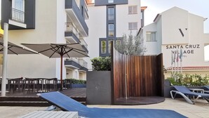 Een terras buiten met loungezetels, een tafel en een houten omheining.