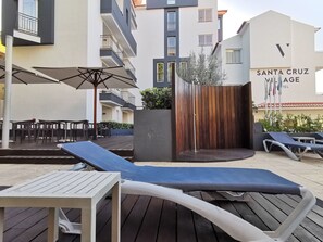 An outdoor patio area with lounge chairs, a table, and a wooden fence. - Santa Cruz Village Hotel (Santa Cruz)