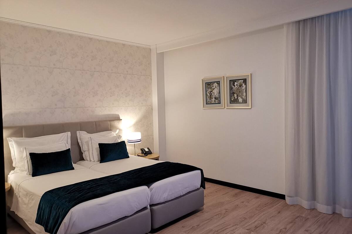 A modern hotel room with a large bed, a bedside lamp, and two framed pictures on the wall.