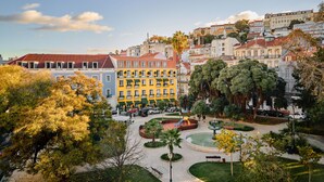 A courtyard with a fountain, surrounded by trees and buildings with balconies.
