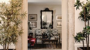 A doorway leading to a room with a mirror, framed artwork, and a patterned chair.