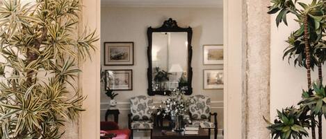 A doorway leading to a room with a mirror, framed artwork, and a patterned chair.