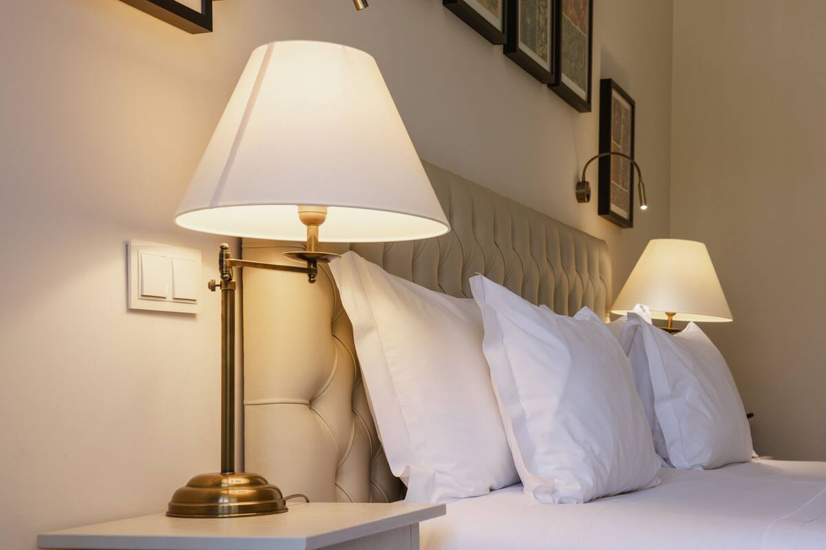 A neatly made bed with white bedding and two bedside lamps.