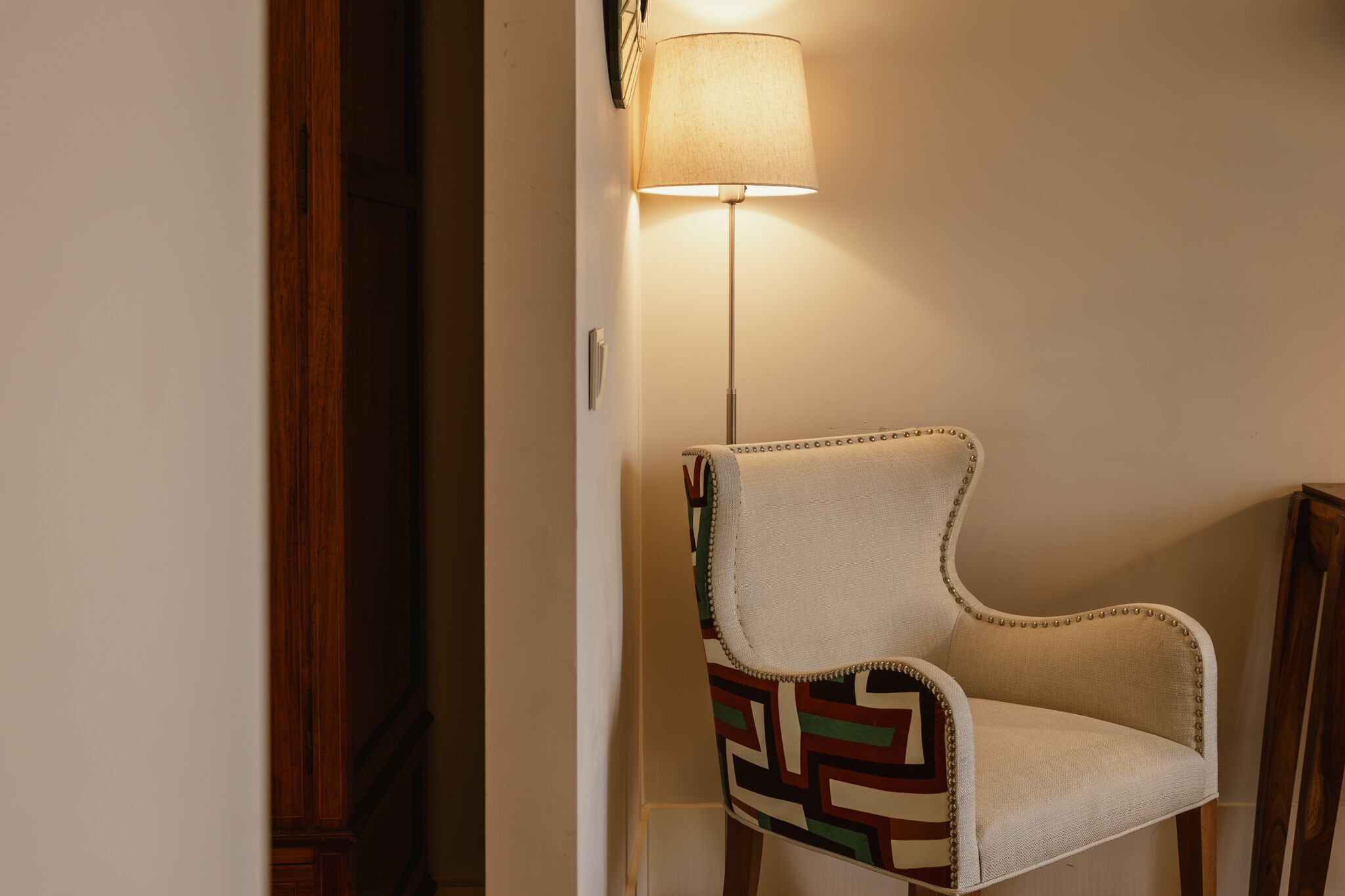 En stol med mønstret stof og en lampe i en gang.