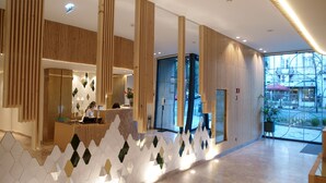 A modern hotel lobby with a reception desk, a large glass door leading outside, and a geometric wall design. - New Style Lisbon Hotel  (Lisbon)